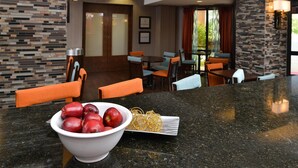 A hotel lobby with a marble reception desk, seating area, and a view of the outdoors. - Hampton Inn Chicago-Carol Stream (Carol Stream)