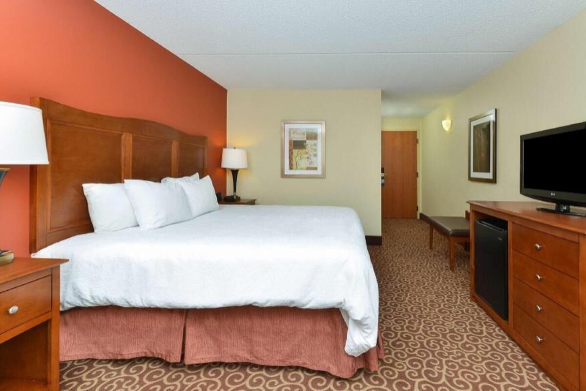 A hotel room with a bed, a TV, a desk, and a dresser.