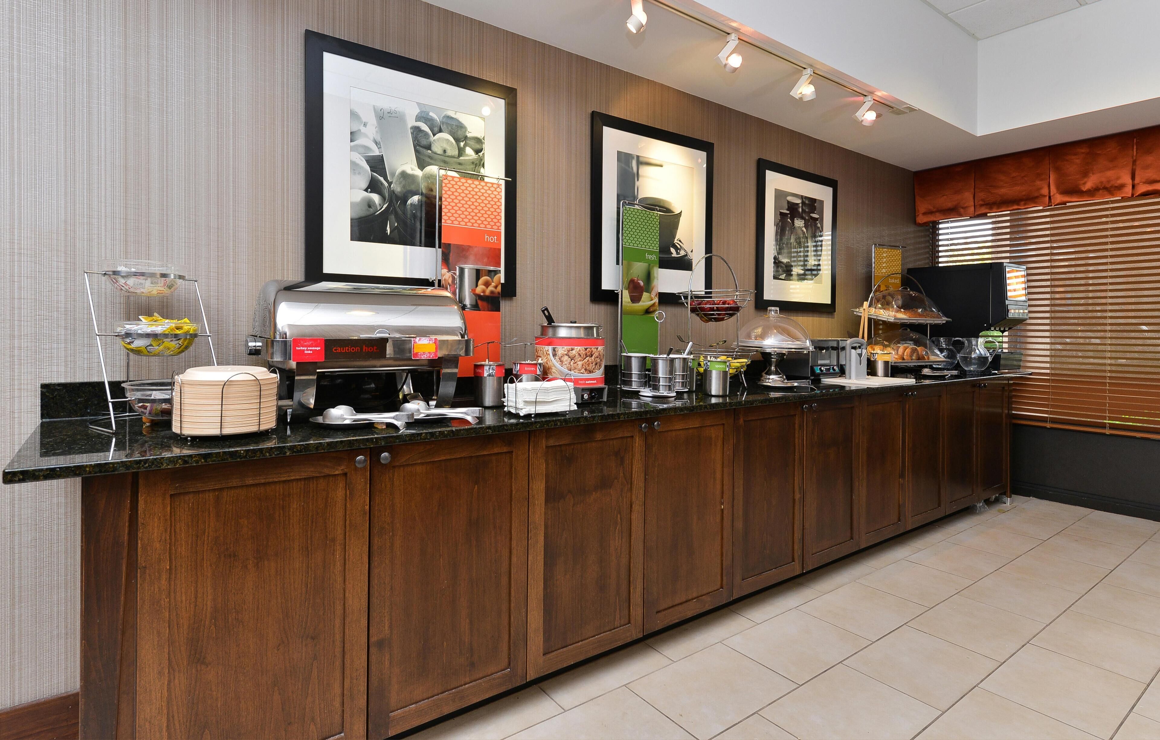 Een hotelkeuken met een lange toonbank, verschillende apparaten en ingelijste foto's aan de muur.