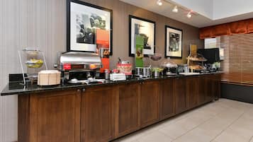 Een hotelkeuken met een lange toonbank, verschillende apparaten en ingelijste foto's aan de muur.