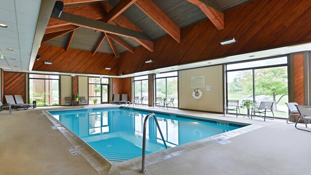 An indoor swimming pool with wooden beams, clear glass walls, and lounge chairs. - Hampton Inn Chicago-Carol Stream (Carol Stream)