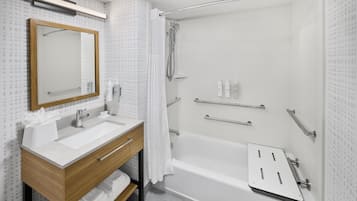 Een moderne badkamer met een houten wastafel, een grote spiegel, een bad en een douche.