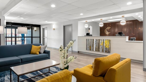 Un hall d’entrée moderne avec un comptoir d’accueil, un canapé bleu, un fauteuil jaune et une table basse.