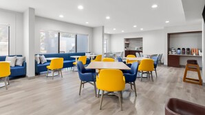Un espace repas moderne avec des canapés bleus, des chaises jaunes et une table en bois.