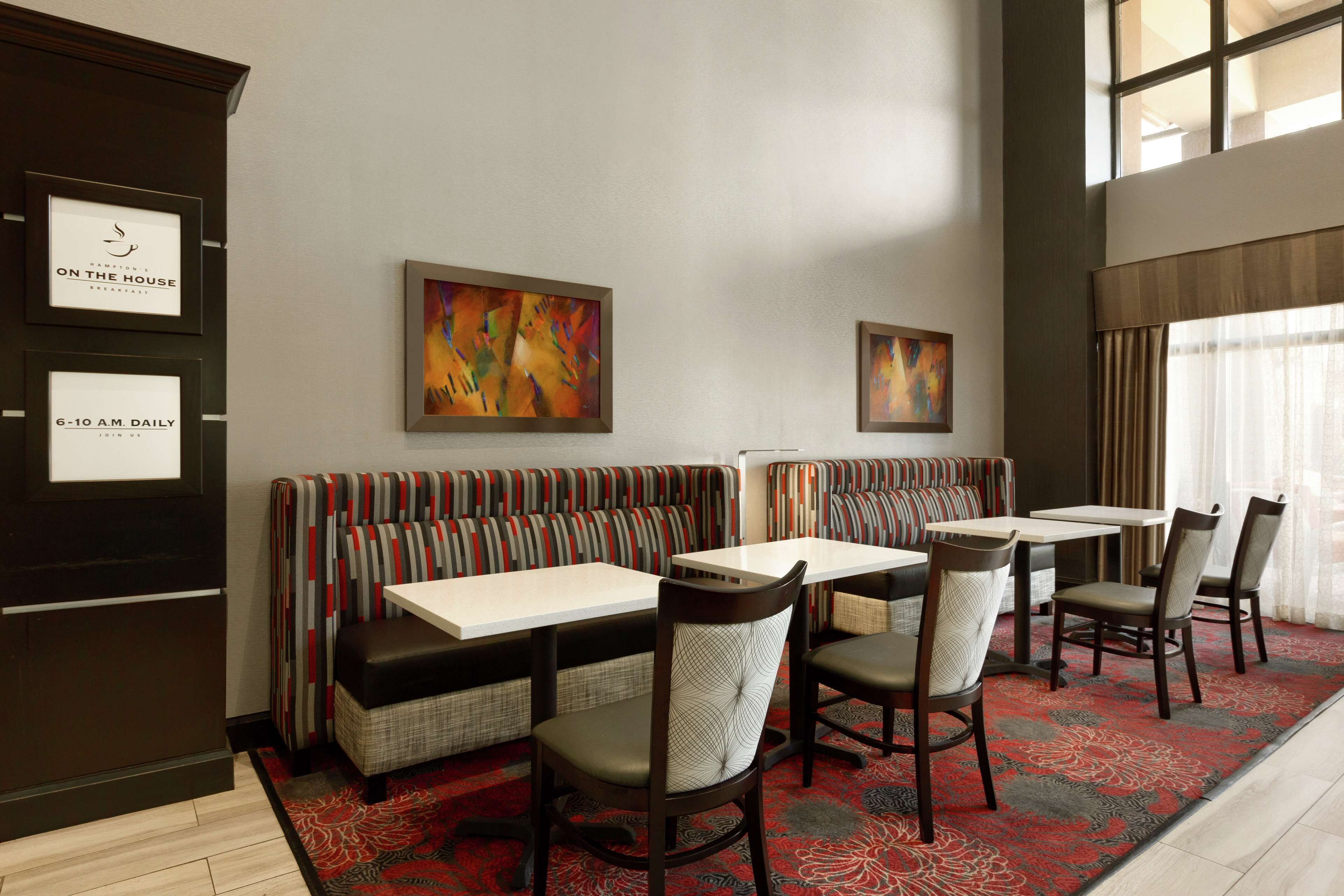 A restaurant with booths, tables, and chairs. There are framed pictures on the wall.