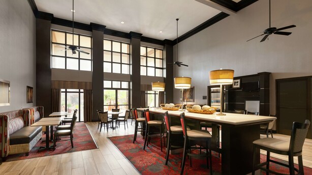 A spacious dining area with high ceilings, large windows, and a central island with chairs.