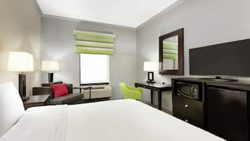 Una habitación de hotel con una cama grande, dos mesitas de noche con lámparas, un escritorio con silla, un televisor, un microondas y un refrigerador.