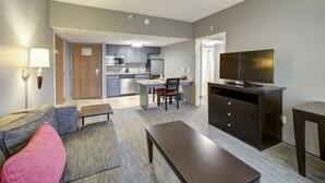A compact living space with a kitchenette, a dining area, and a TV.