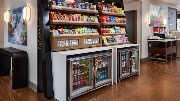 A snack display with various packaged foods and a refrigerated section with beverages. - Hampton Inn Massillon (Massillon)