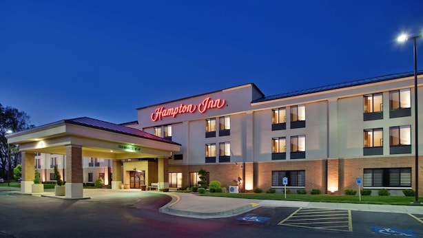 Un hôtel Hampton Inn avec une entrée bien visible, un parking et un panneau indiquant les places de stationnement réservées aux personnes handicapées.