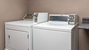 A laundry area with two white front-loading washers and a commercial washer.