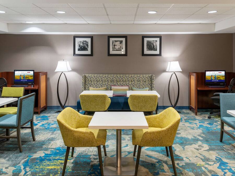Een hotelkamer met een groot bed, een bureau met een computer en een zithoek met stoelen en een tafel.