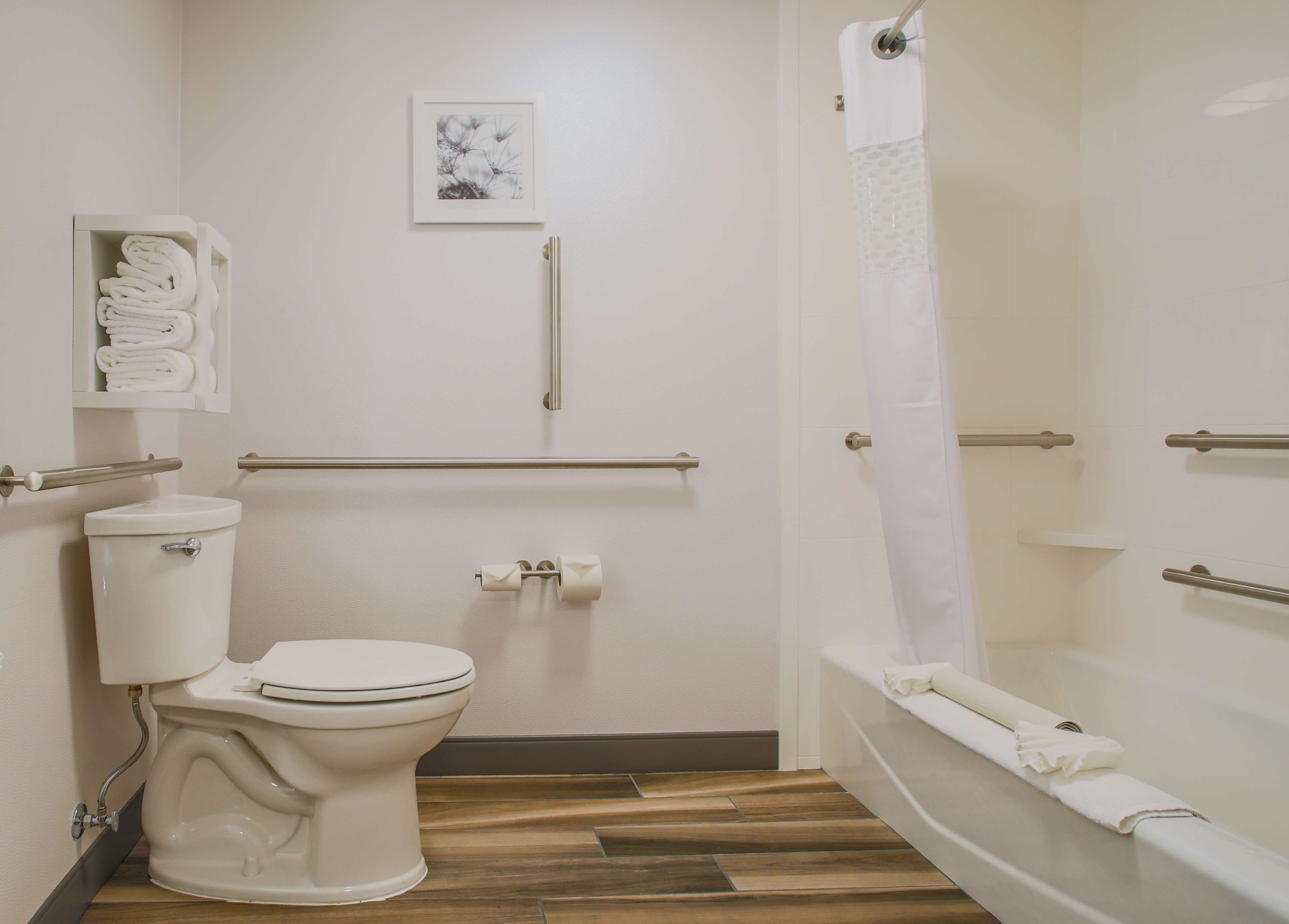 Un bagno moderno con WC, bidet e vasca da bagno. Sono presenti maniglioni e un porta asciugamani.