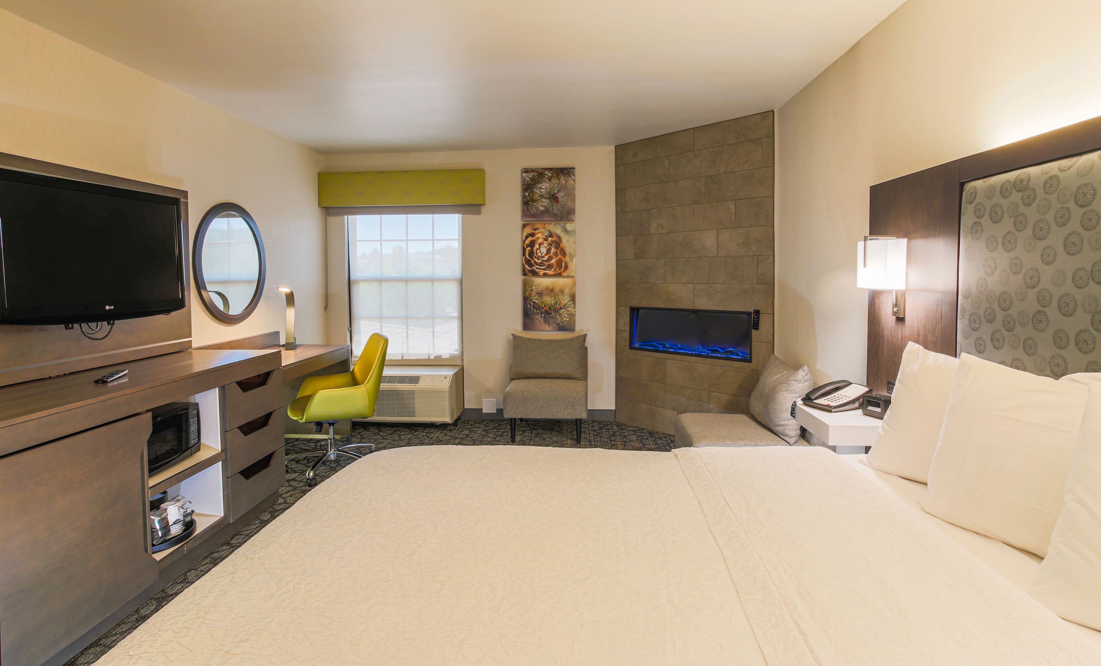 Une chambre d’hôtel comprenant un lit, un bureau avec une chaise, une télévision, une cheminée et un téléviseur fixé au mur.