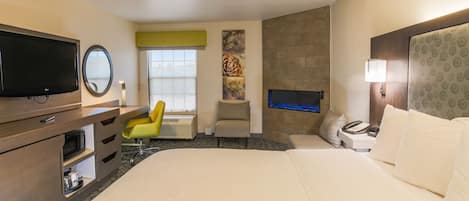 Une chambre d’hôtel comprenant un lit, un bureau avec une chaise, une télévision, une cheminée et un téléviseur fixé au mur.