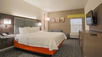 Habitación de hotel con una cama grande, mesita de noche con teléfono, escritorio con televisor de pantalla plana y un calentador de pared.