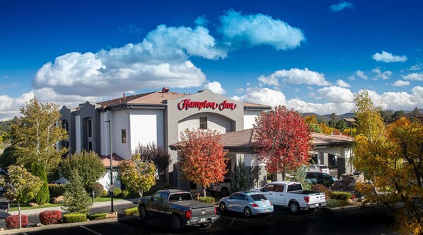 A Hampton Inn hotel with a modern design, parking lot, and surrounding trees.