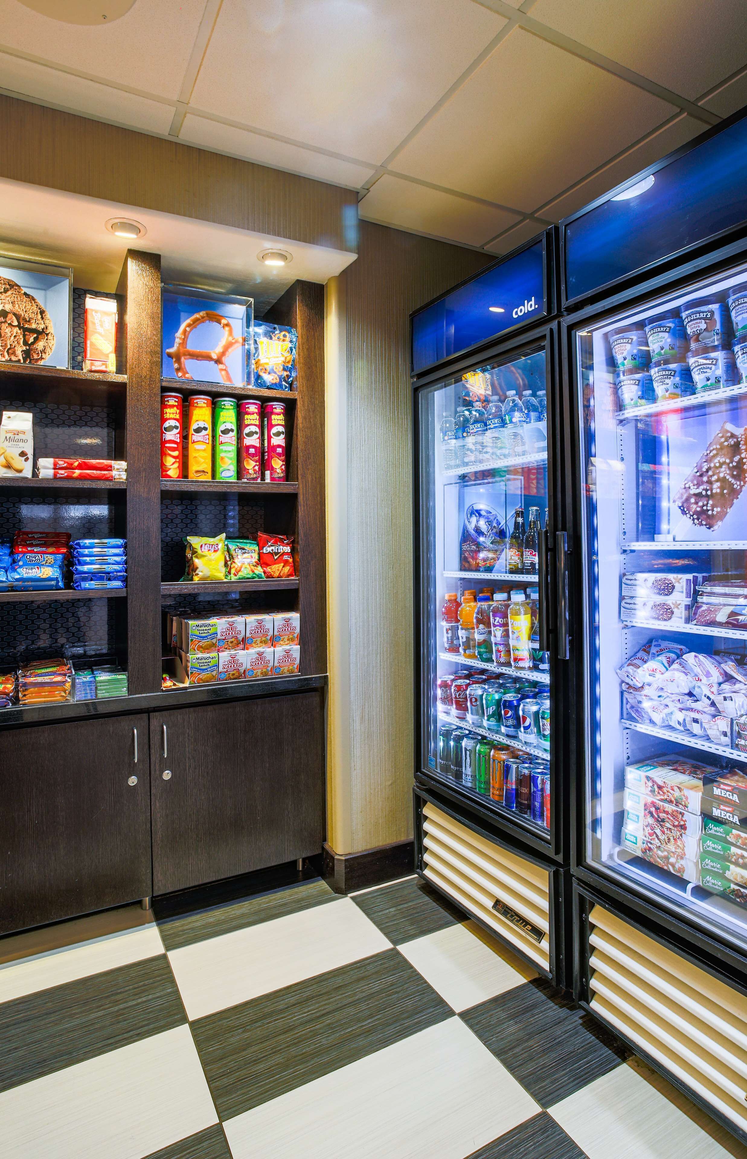 Zona de máquinas expendedoras con aperitivos, bebidas y una sección refrigerada.