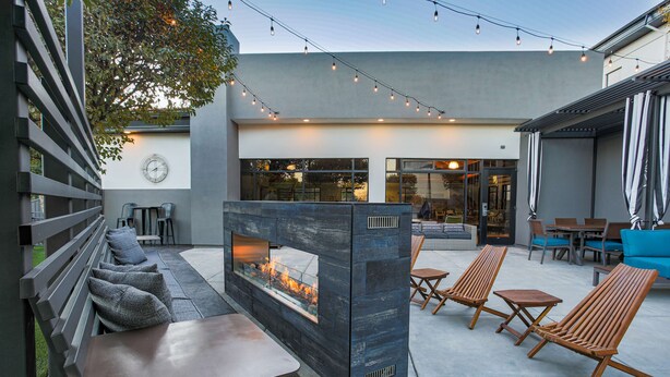 An outdoor patio with a built-in fire feature, seating, and string lights.
