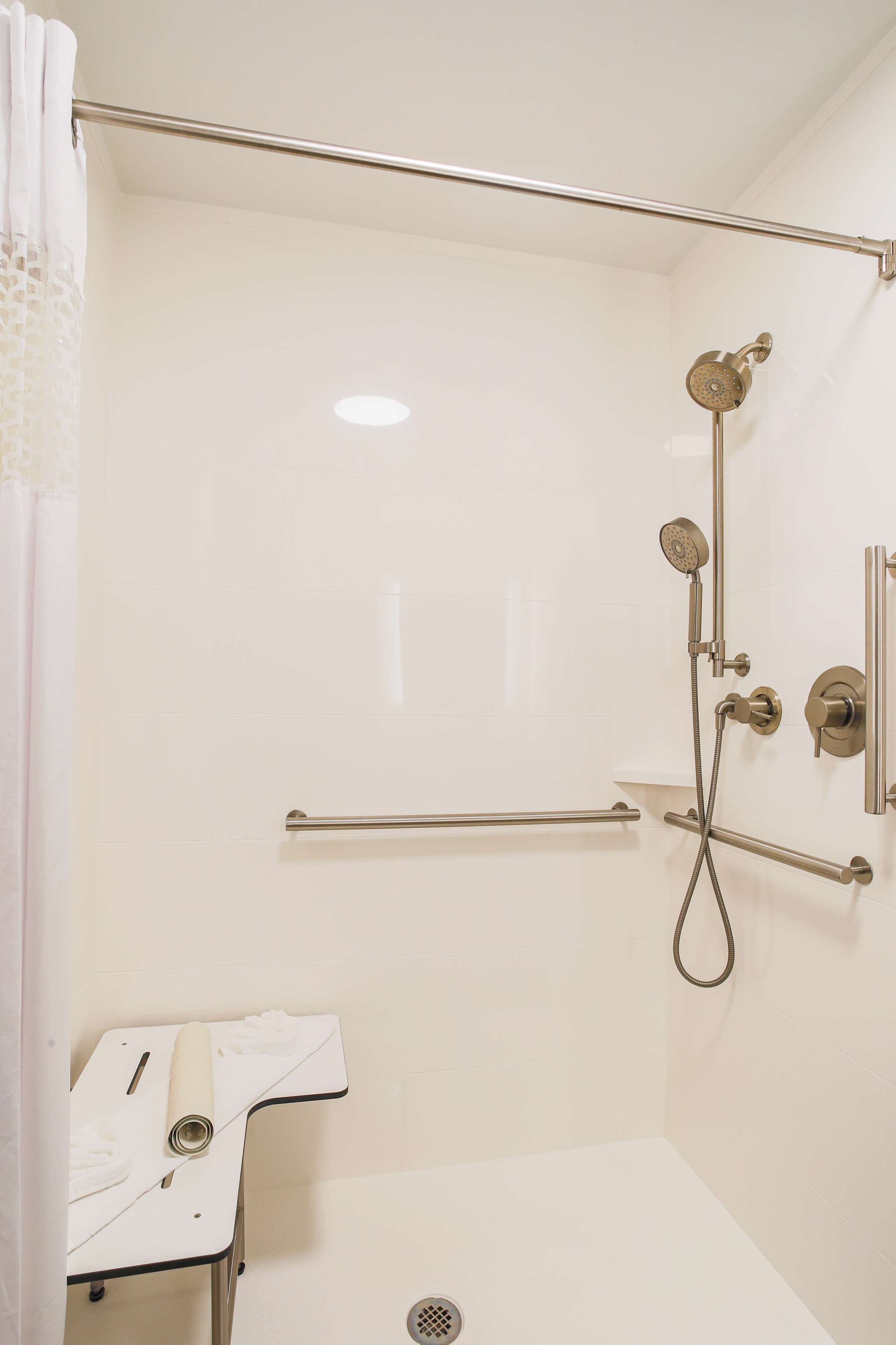 A shower area with a handheld showerhead, a wall-mounted faucet, and a grab bar.