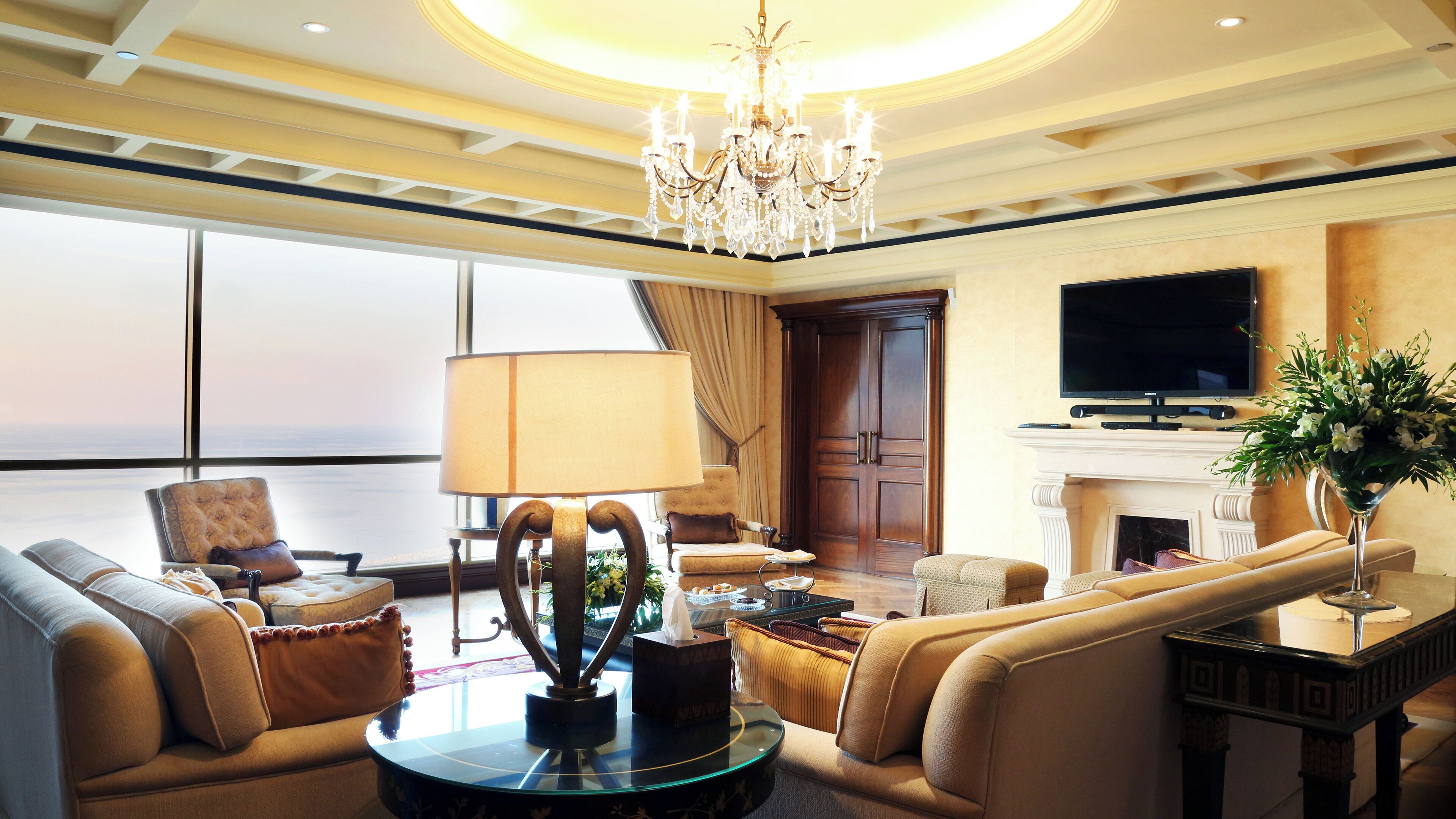 A spacious living room with a chandelier, sofas, a television, and a fireplace.