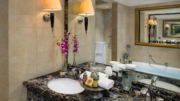 A bathroom with two sinks, marble countertops, a large mirror, and wall-mounted lamps.