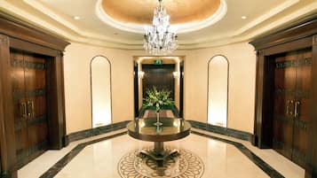 A lobby with a round table, a chandelier, and wooden doors.