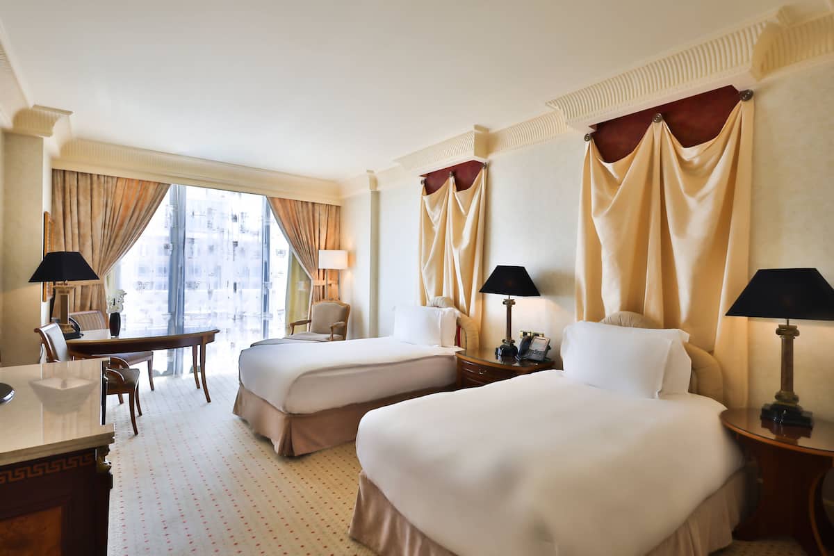 Une chambre d’hôtel avec deux lits, un bureau et une chaise.