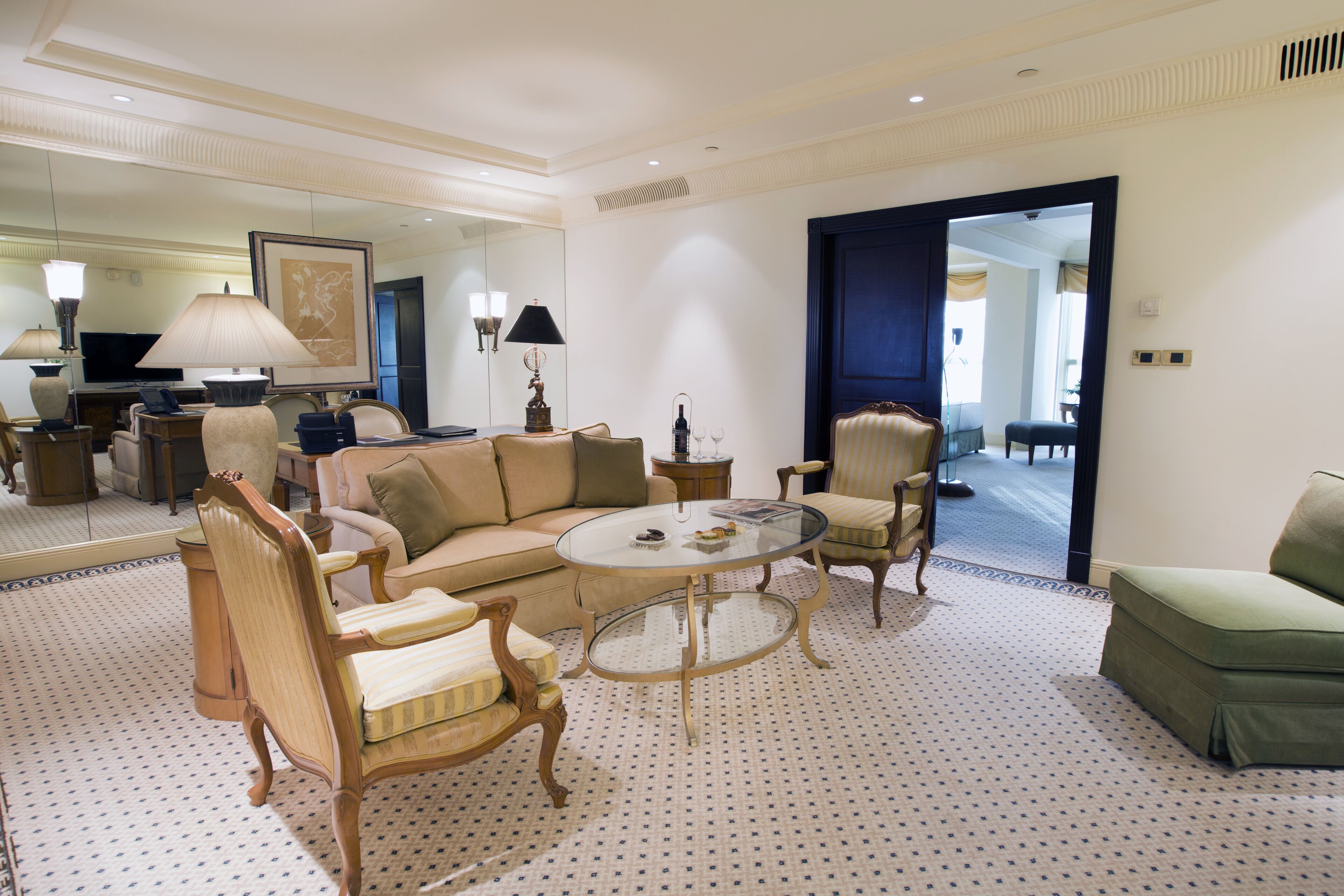 A spacious living room with a sofa, armchairs, a coffee table, and a television.