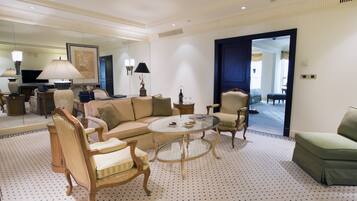 A spacious living room with a sofa, armchairs, a coffee table, and a television.