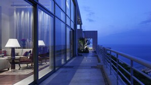 Un moderno cuarto de hotel con amplios ventanales, un sofá, una lámpara y vista al mar.