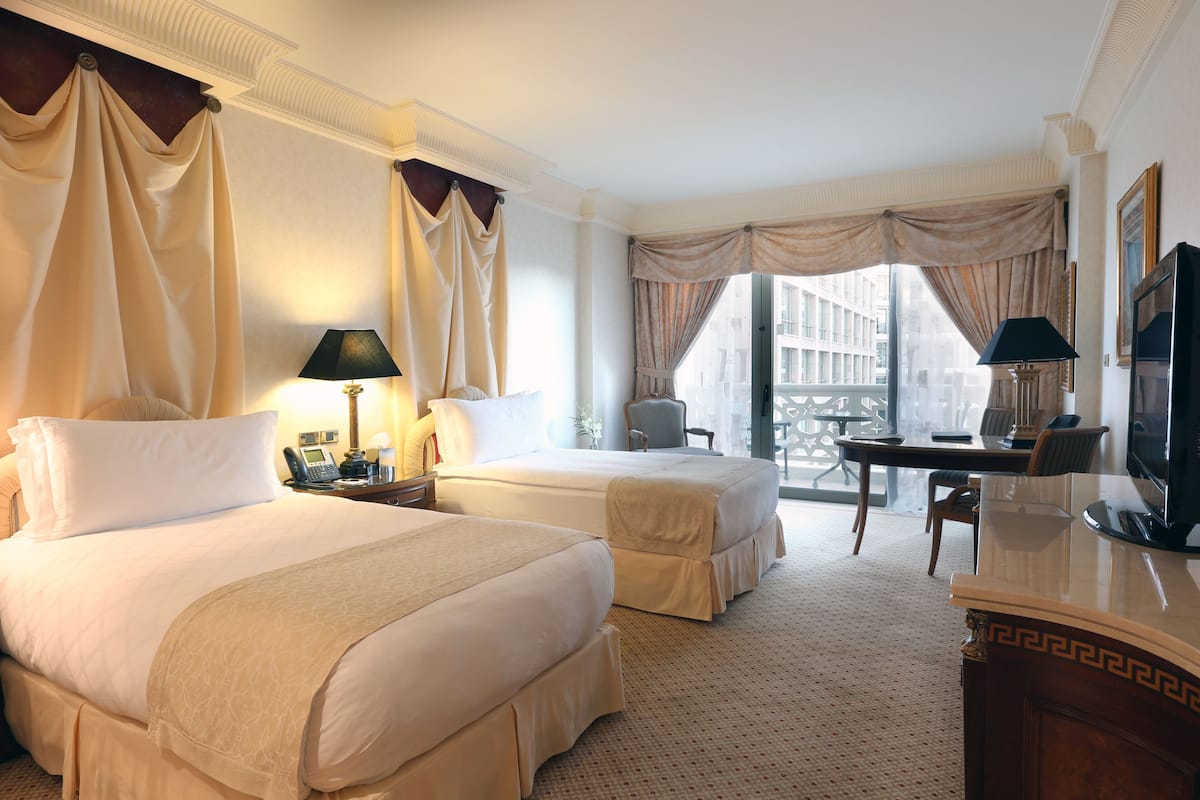 Une chambre d’hôtel avec deux lits, un bureau, une télévision et une vue sur la ville.