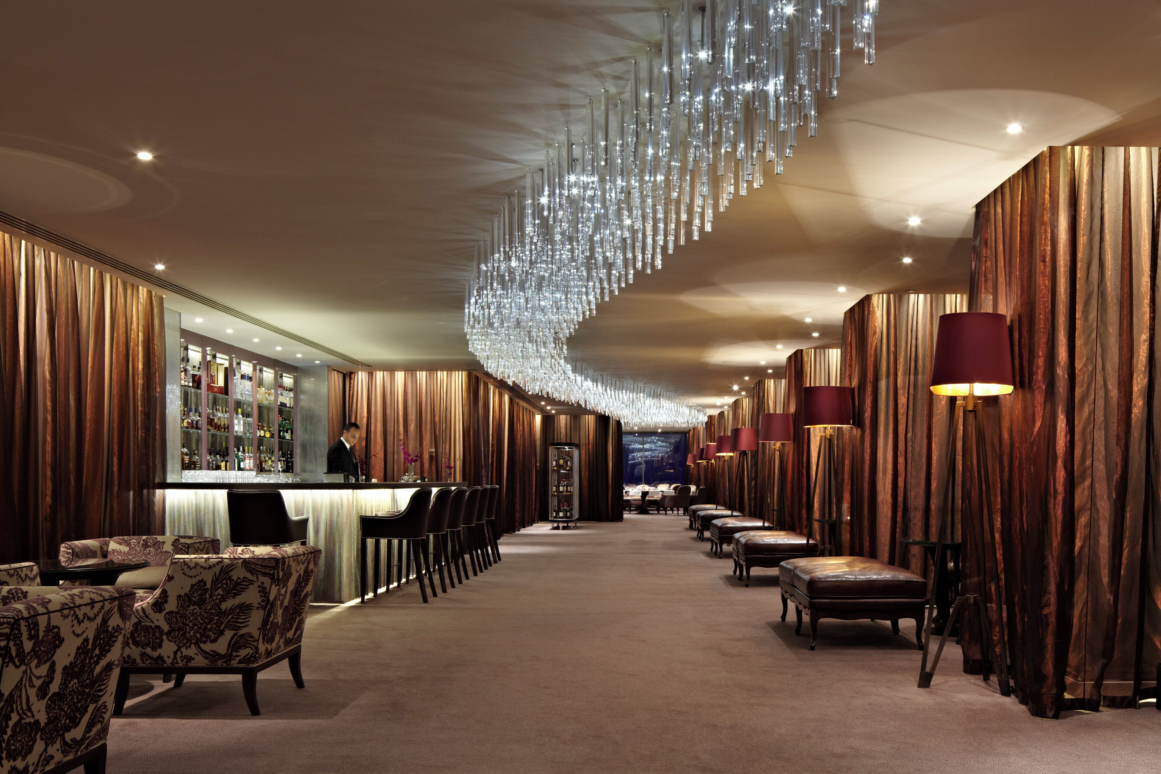 A hotel lobby with a bar area, seating, and a chandelier.