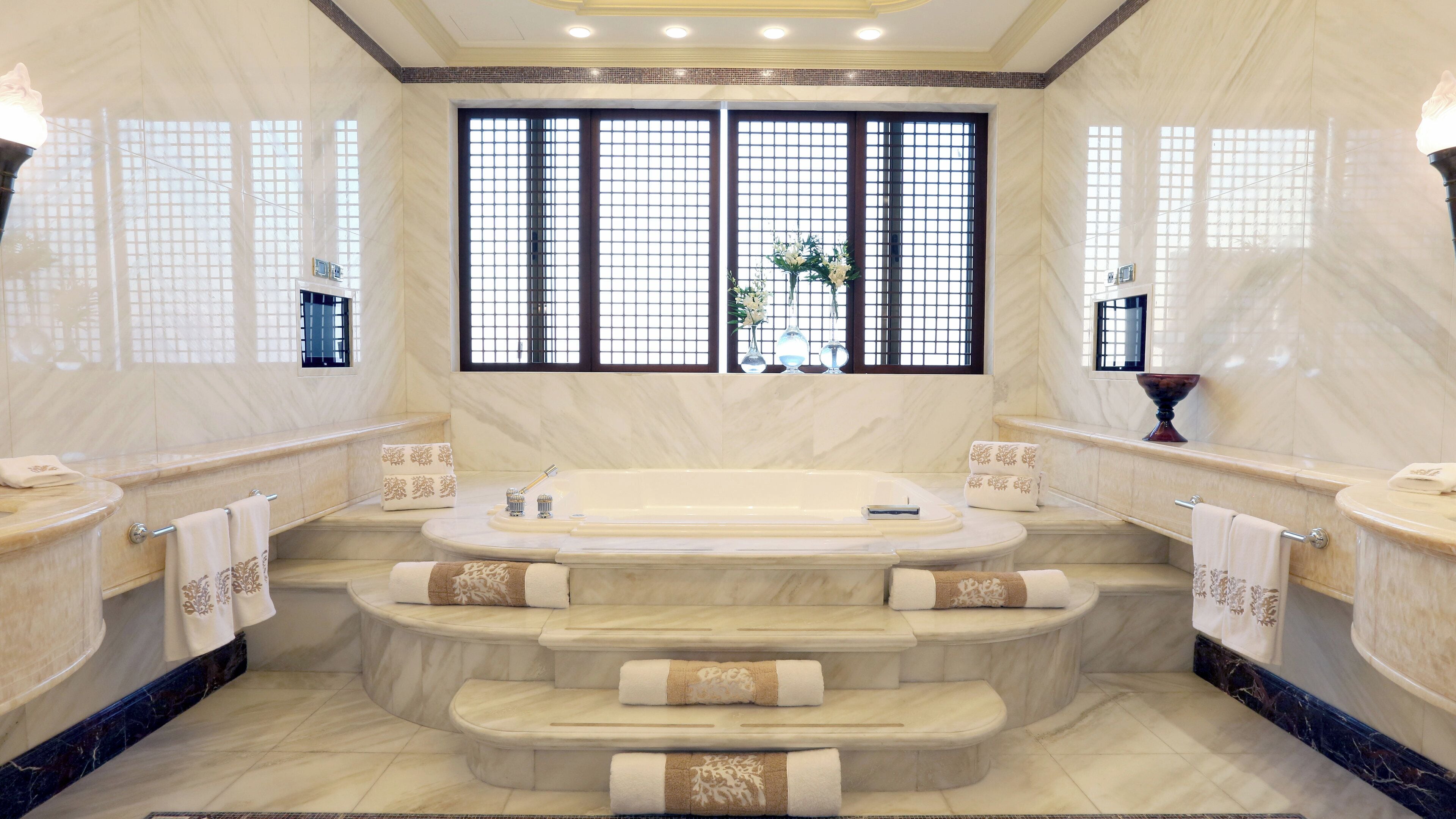 A luxurious bathroom with a freestanding bathtub, marble flooring, and a large window with a view.