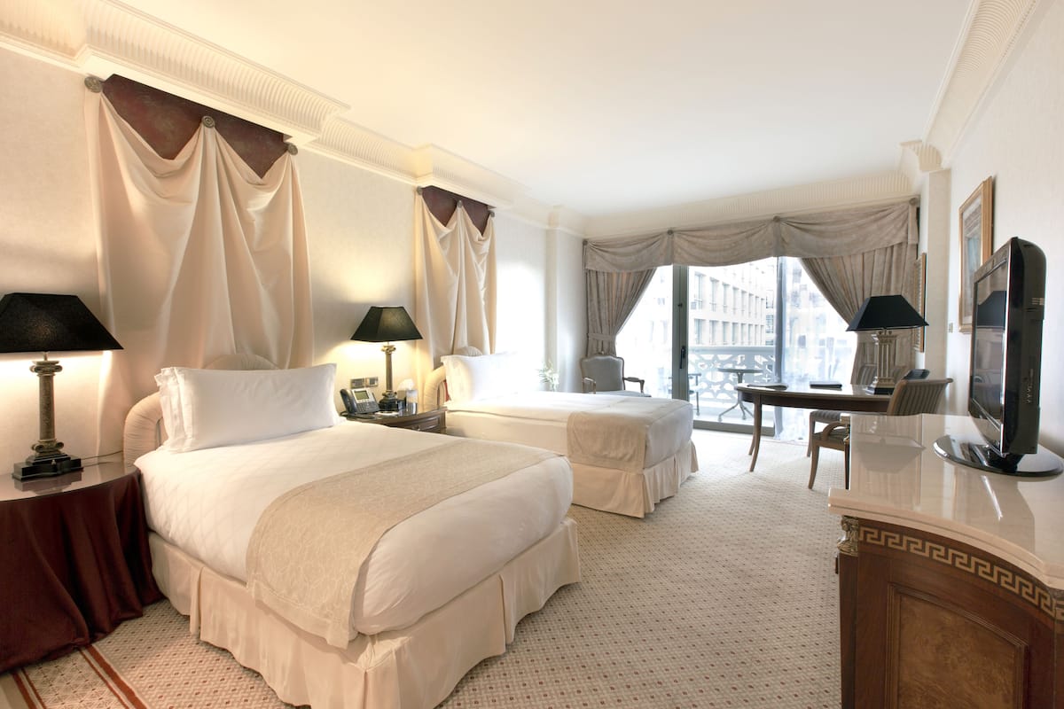 Une chambre d’hôtel avec deux lits, un bureau, une télévision et de grandes fenêtres.