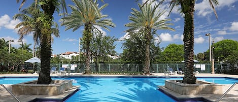 Una piscina al aire libre, sombrillas, sillones reclinables de piscina