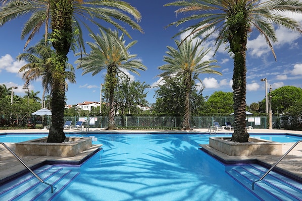 Una piscina al aire libre, sombrillas, sillones reclinables de piscina