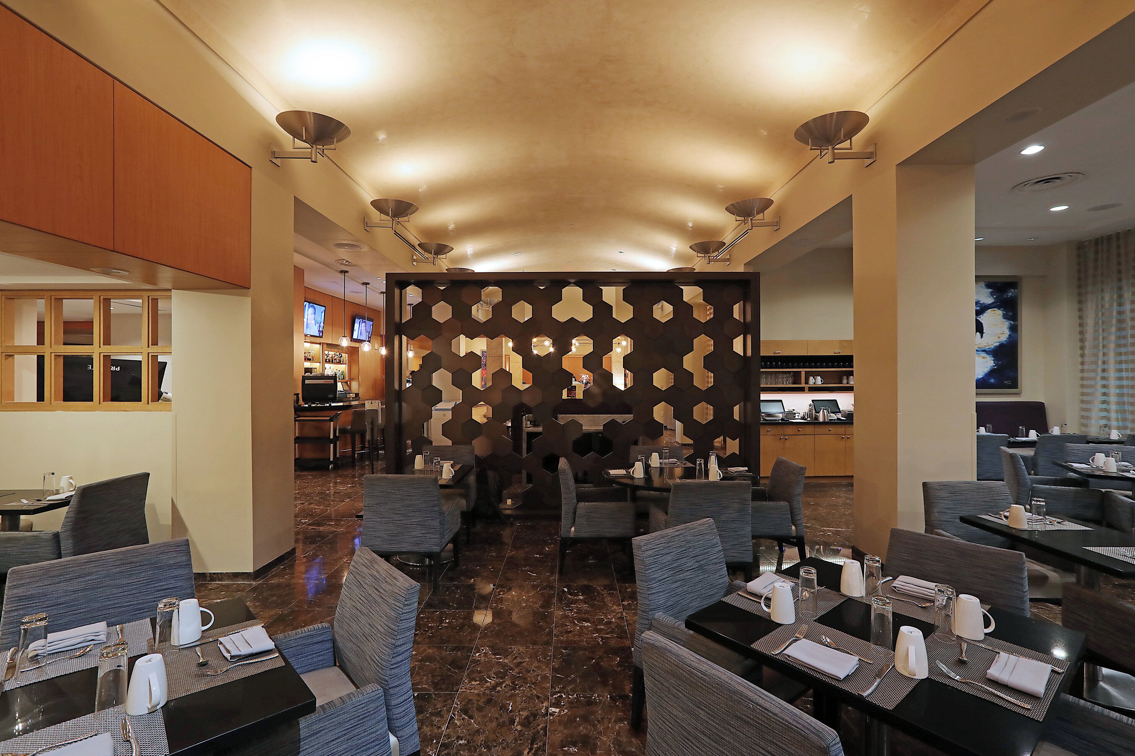 A hotel lobby with seating areas, a reception desk, and a bar.