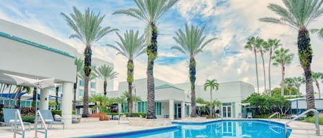 A swimming pool surrounded by palm trees and modern buildings.