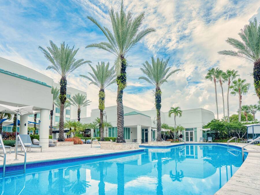 Una piscina rodeada de palmeras y edificios modernos.