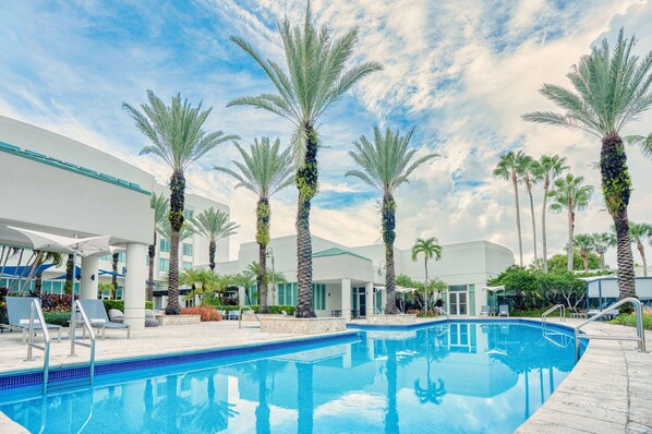 A swimming pool surrounded by palm trees and modern buildings.