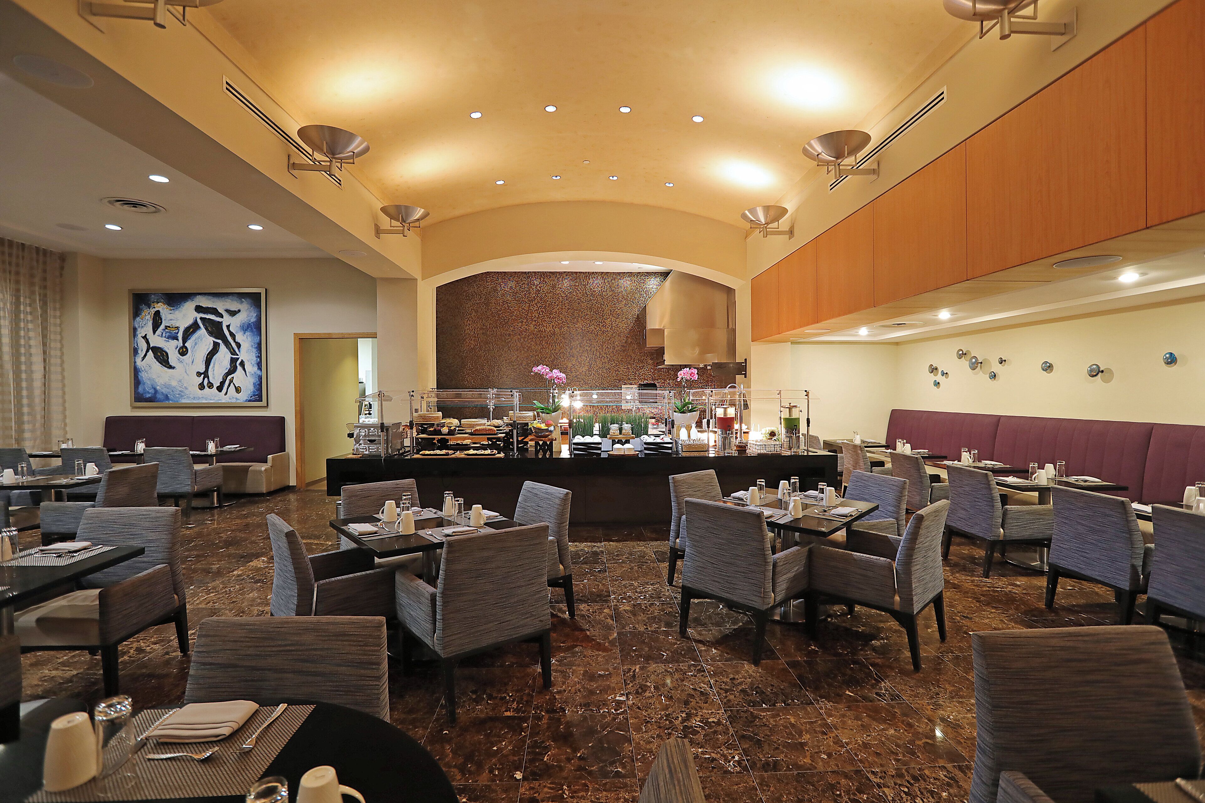 A spacious restaurant with high ceilings, marble flooring, and a central bar area.