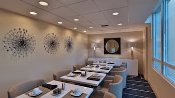 Un comedor de hotel con varias mesas, sillas y decoración mural.