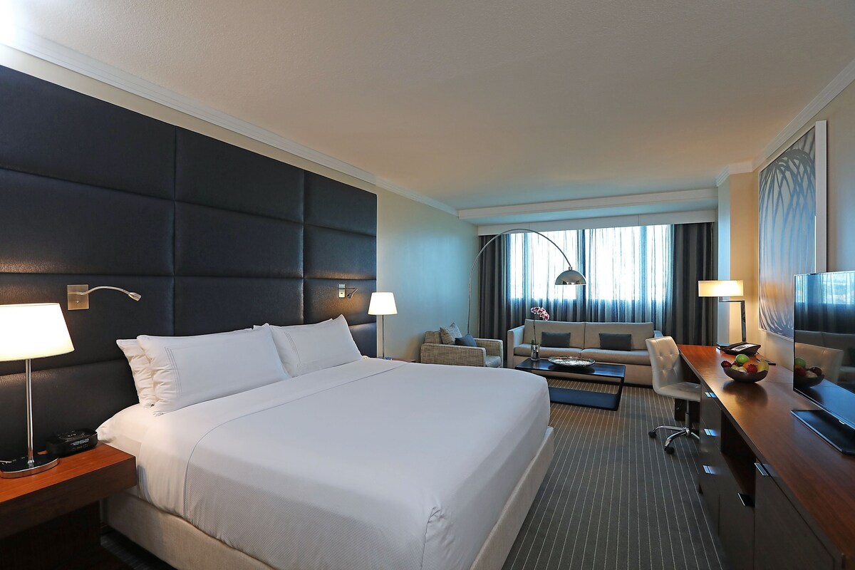 Een hotelkamer met een groot bed, een bureau met een televisie, een bank en een eettafel.
