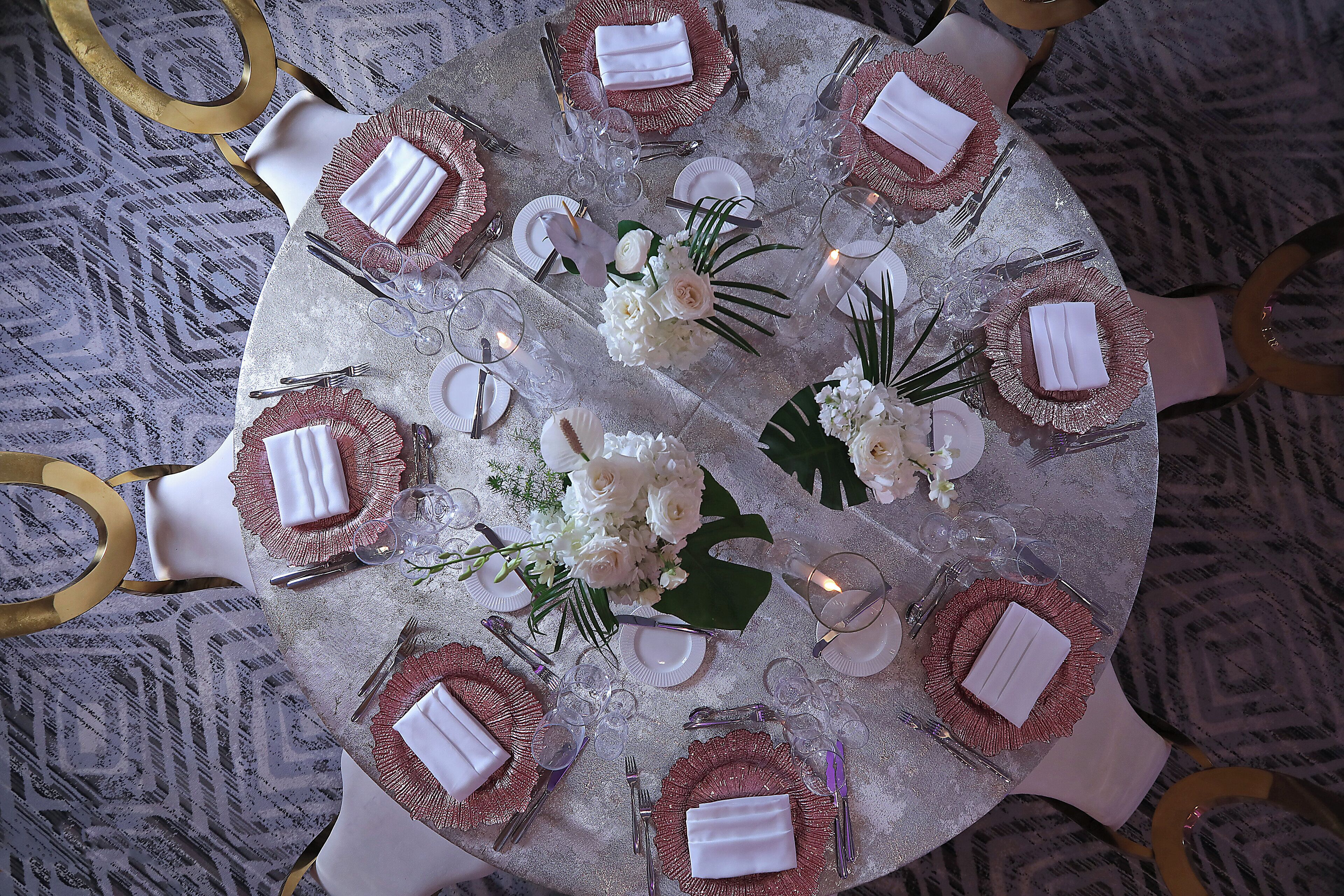 A round table with a white tablecloth, gold chairs, and a central floral arrangement.
