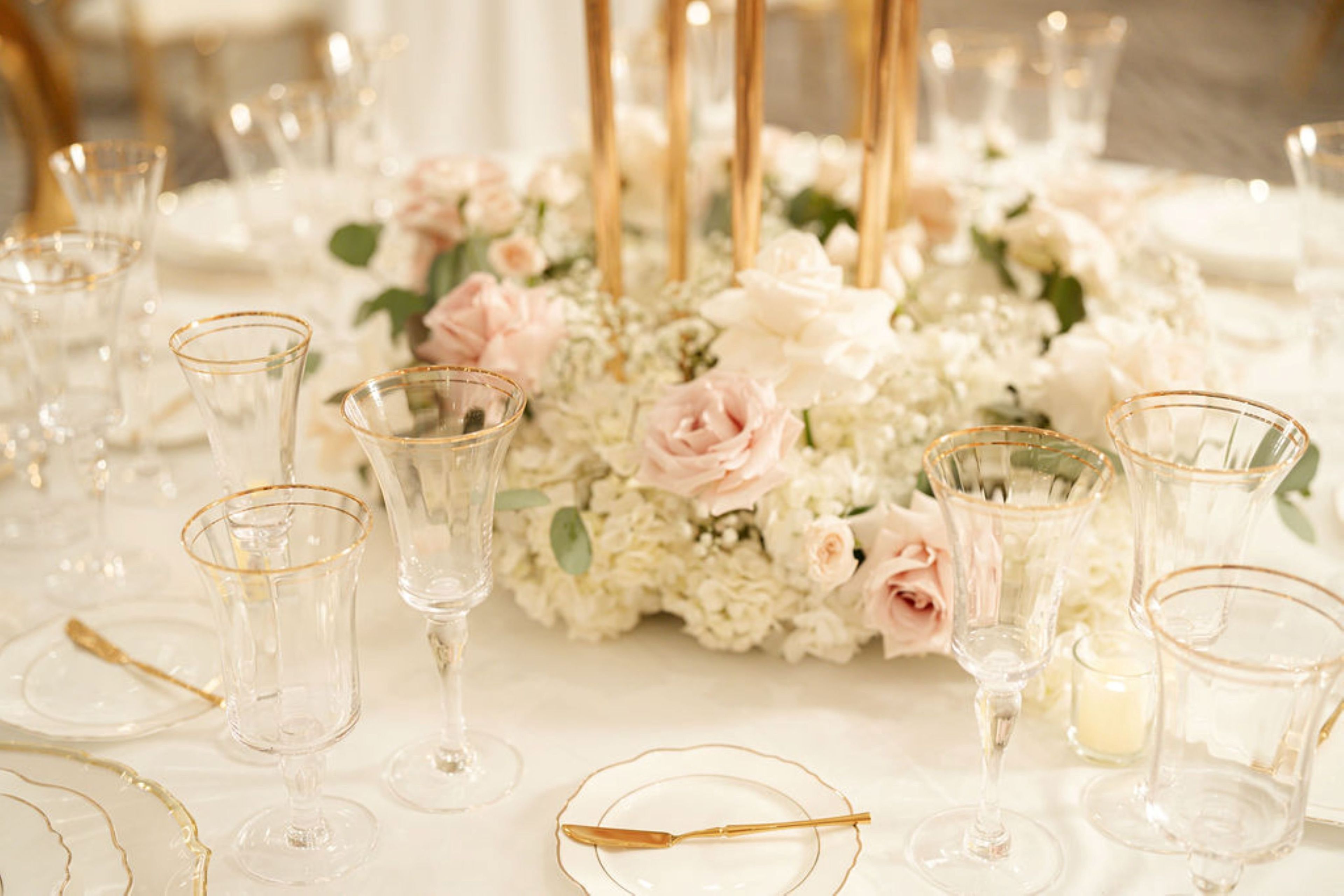 A table set for a formal event with clear glassware and floral centerpieces.