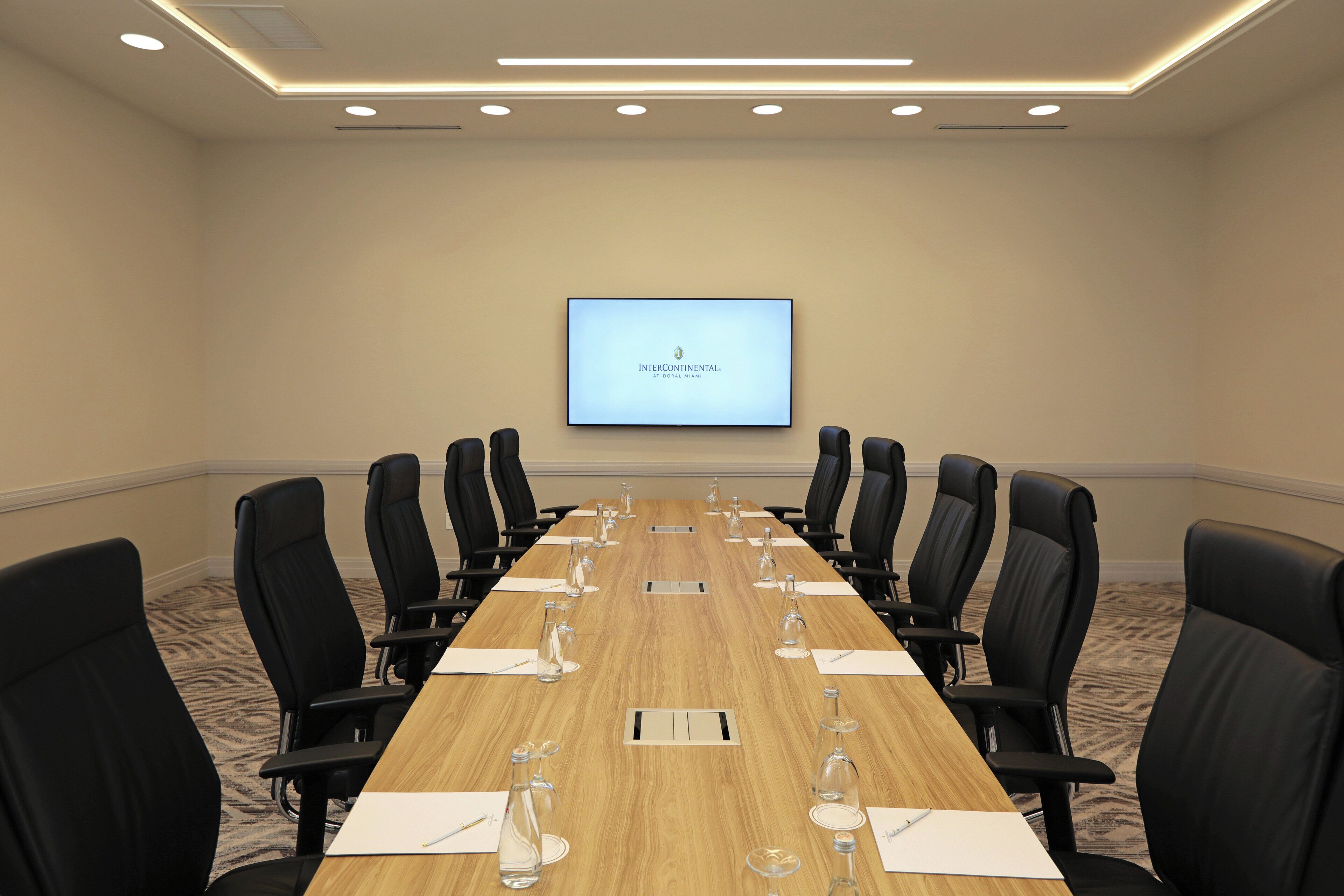 Un salón de conferencias con una larga mesa, sillas negras y una pantalla que muestra "INTERCONTINENTAL".