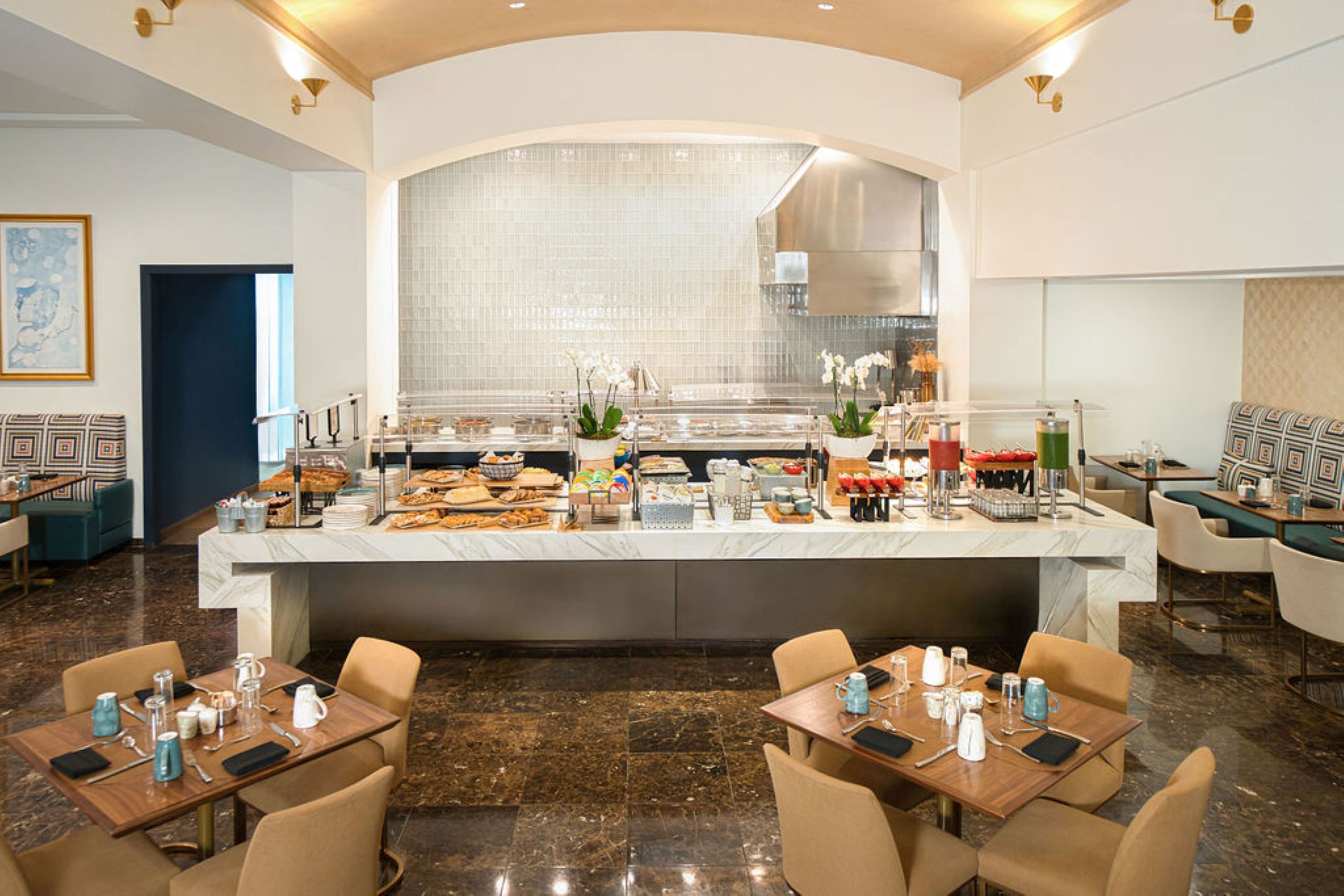 A breakfast bar with seating, a tiled backsplash, and a modern kitchen in the background.