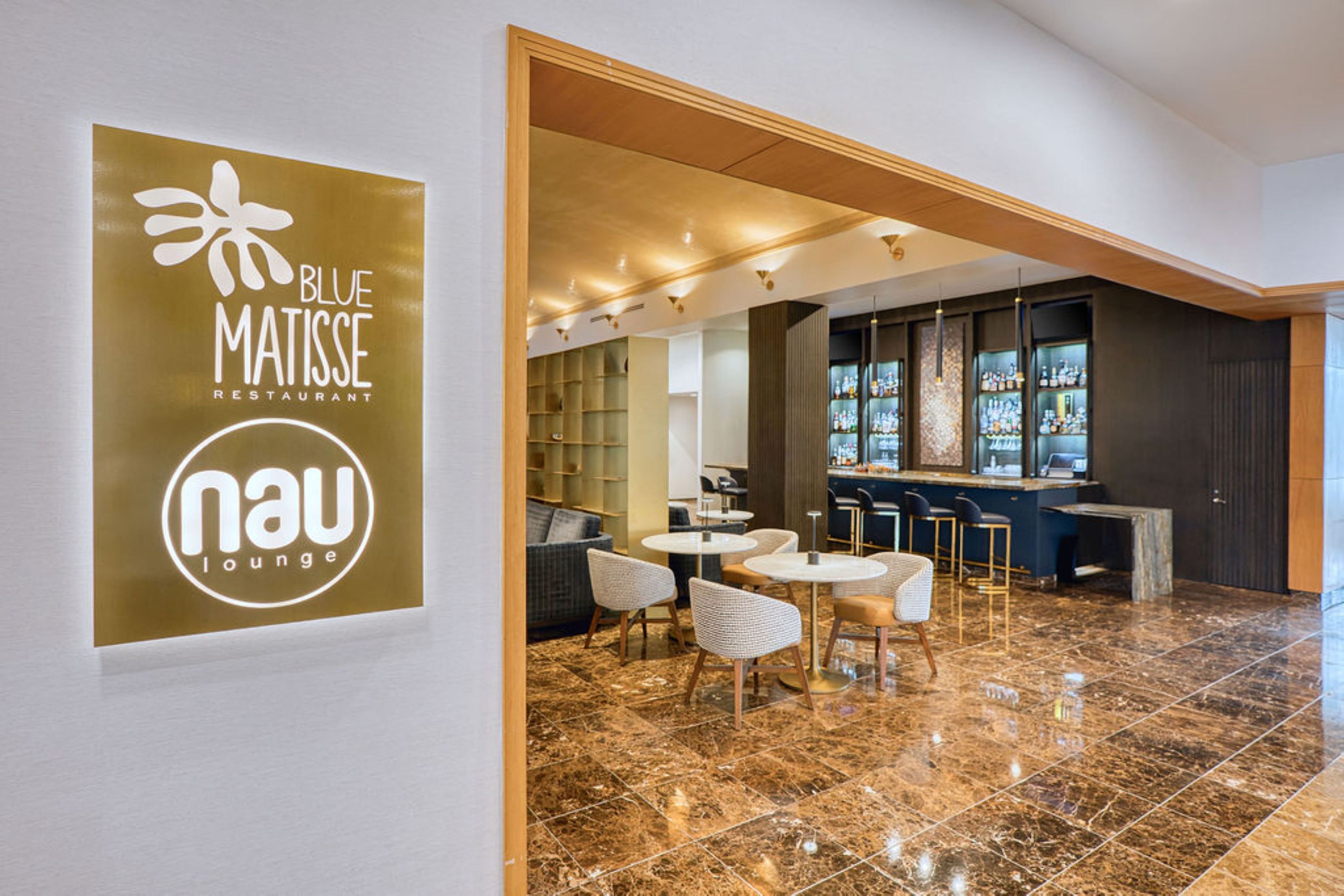 A modern interior with a bar area, seating, and a sign for 'Blue Matisse Restaurant'.