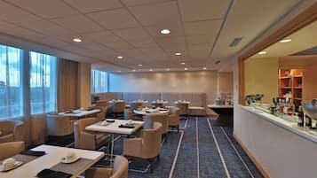 A hotel lobby with seating areas, a bar, and a view of the outdoors.
